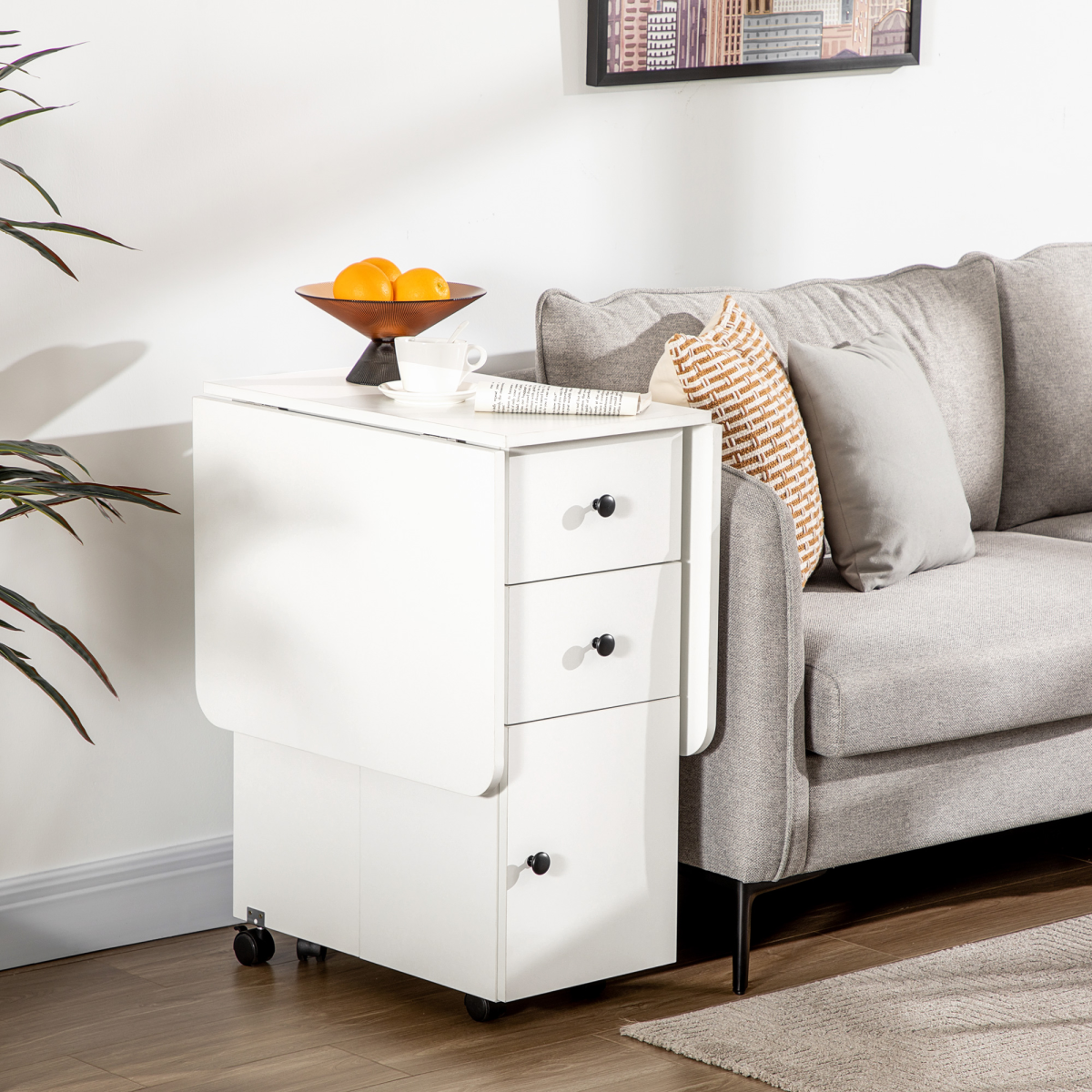 White drop‑leaf folding dining table with storage drawers.