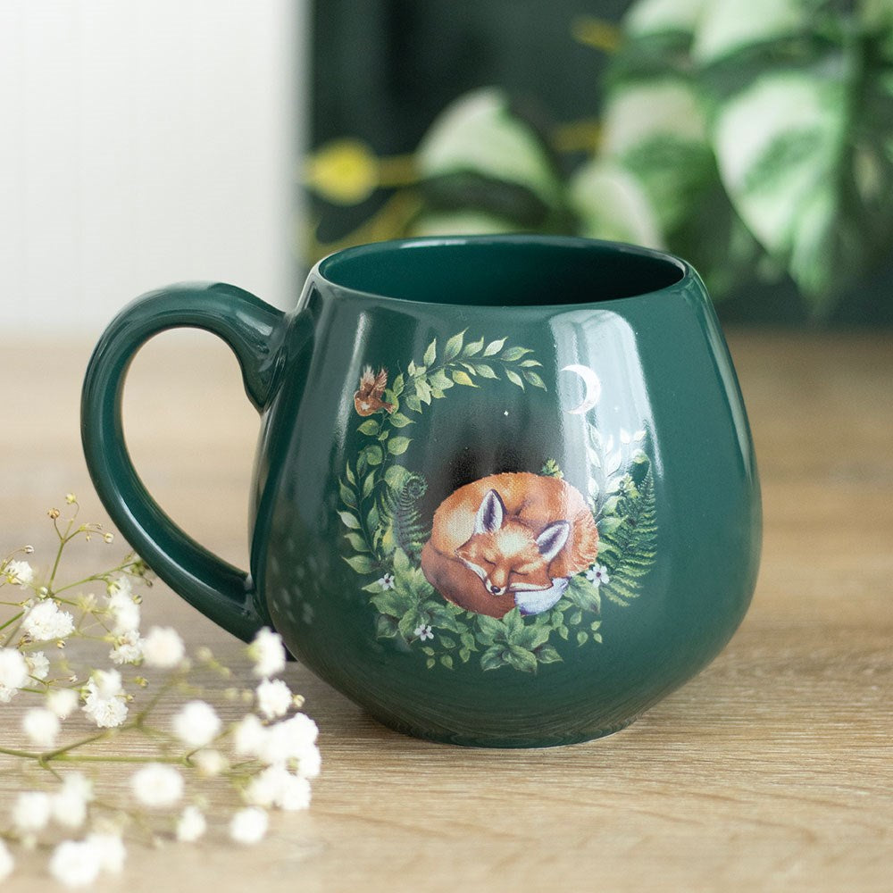 Green ceramic mug with a sleeping fox among ferns