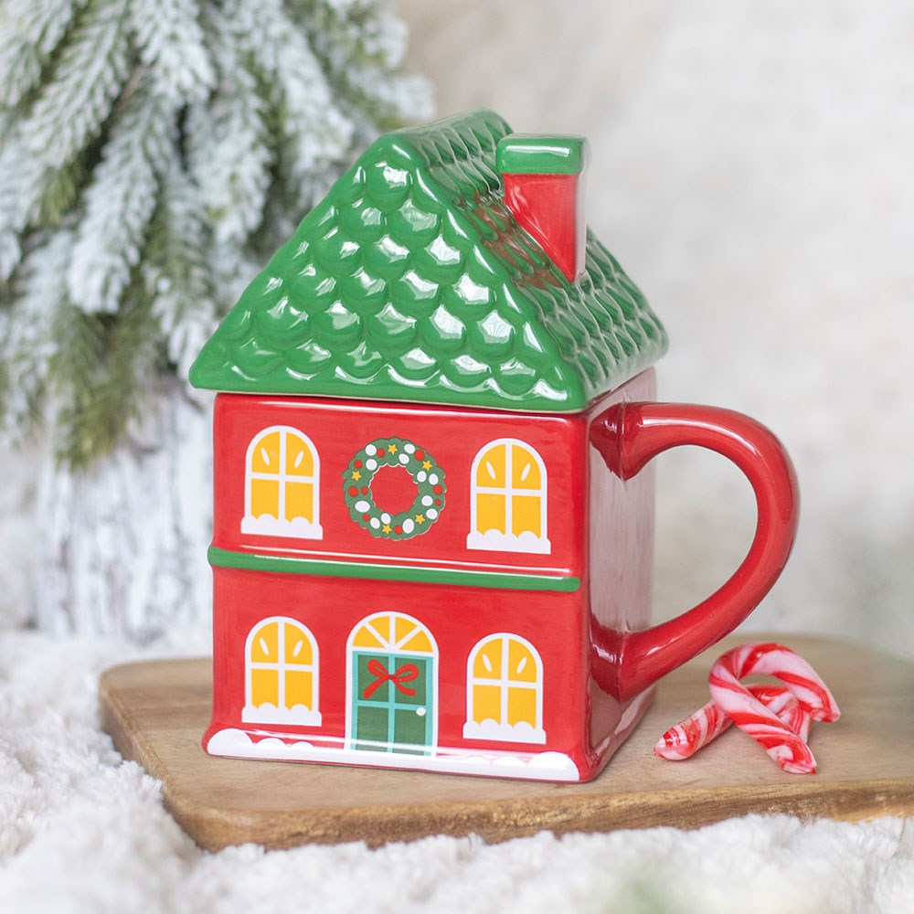 Ceramic mug shaped like a red Christmas house with a green roof lid and lit windows